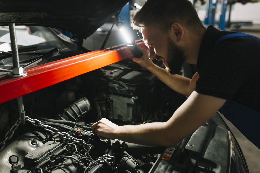 Monteur controleert de motor met een looplamp bij Garage Duiven
